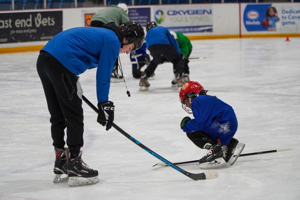 A coach crouched down adjusting a camper stick grip