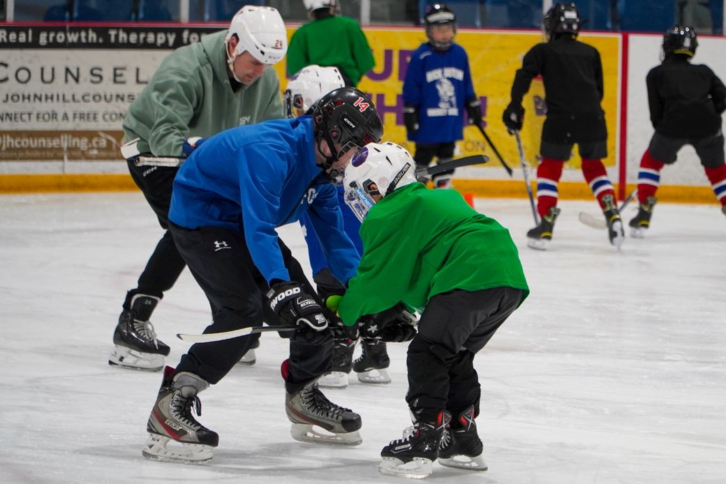 A coach and camper face to face working through a puck handling drill