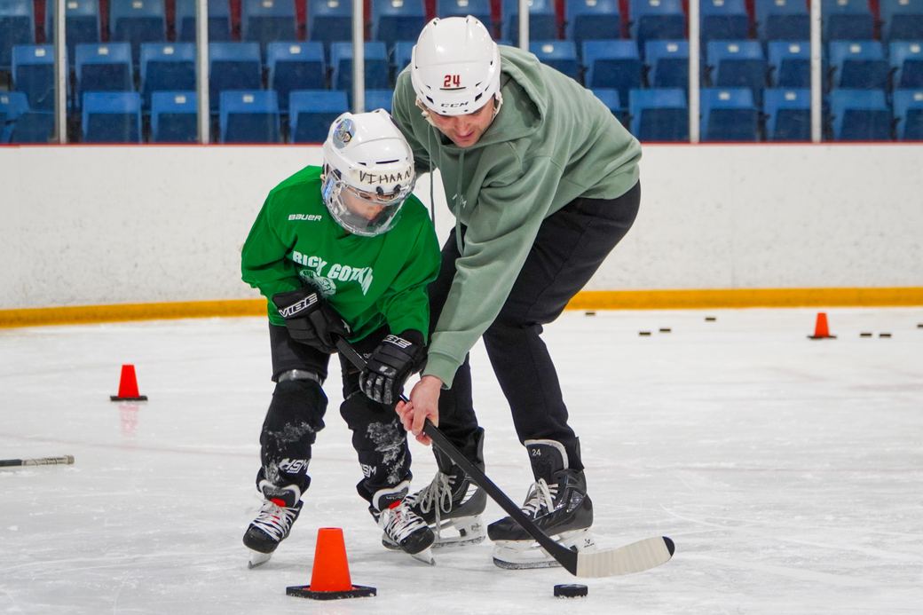 Campers weaving a puck through orange cones with a volunteer guiding