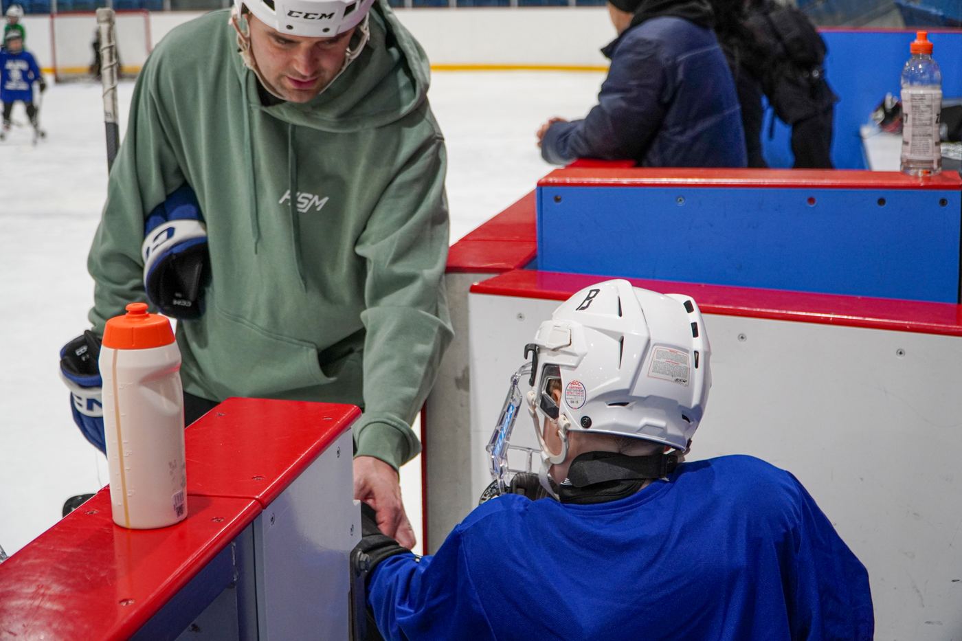 A coach leaning on the boards watching campers during media day