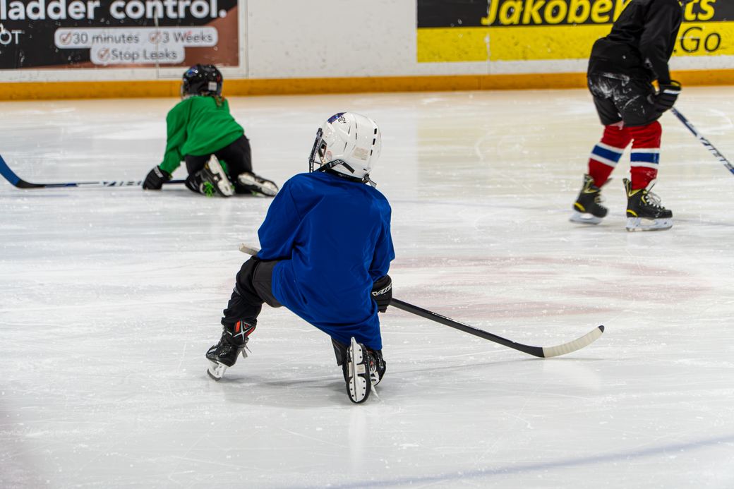 A camper in green edging along the boards with a volunteer a step behind