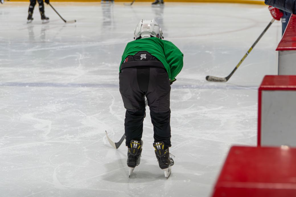 A camper in green skating slowly toward the far boards