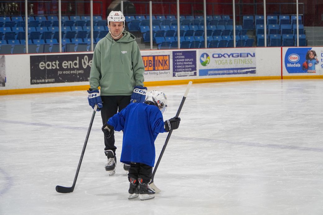 A beginner in blue taking careful strides with a coach watching