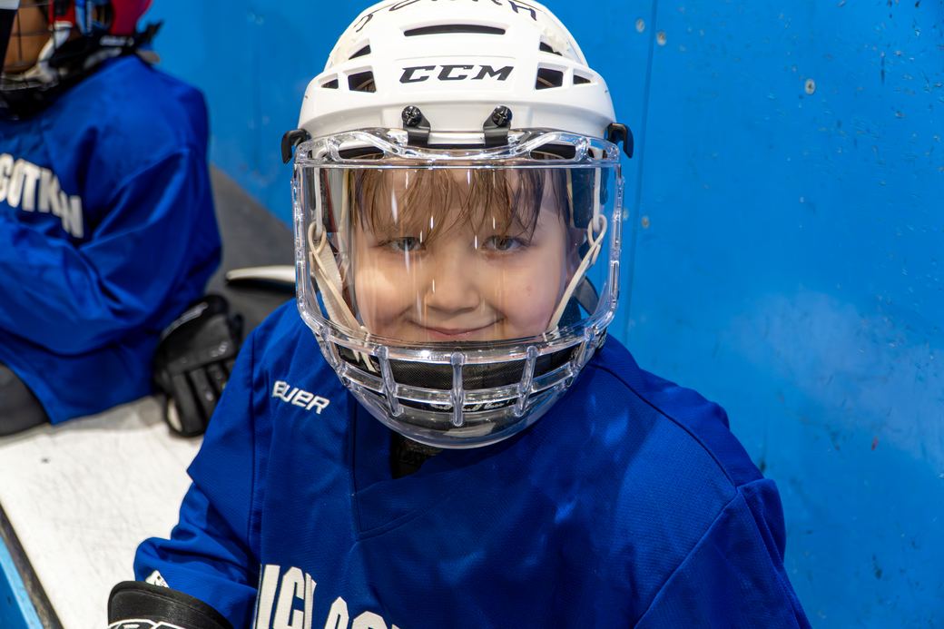 A camper in a blue jersey and cage helmet laughing