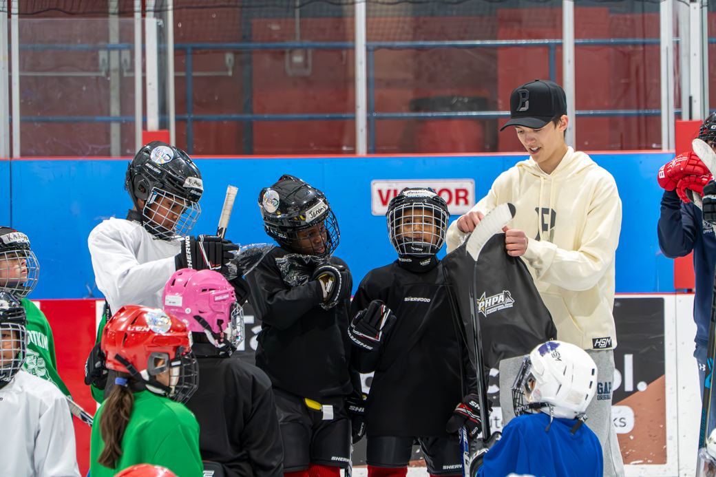 Student volunteers handing equipment bags to campers along the boards