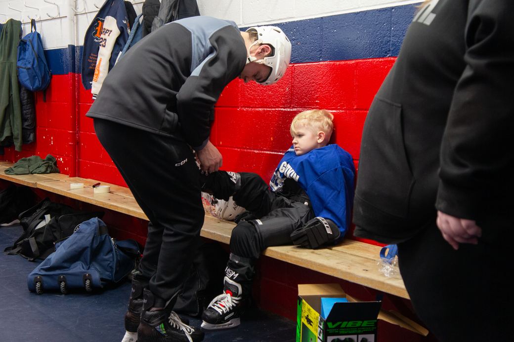 Campers on the bench pulling on shin pads before taking the ice
