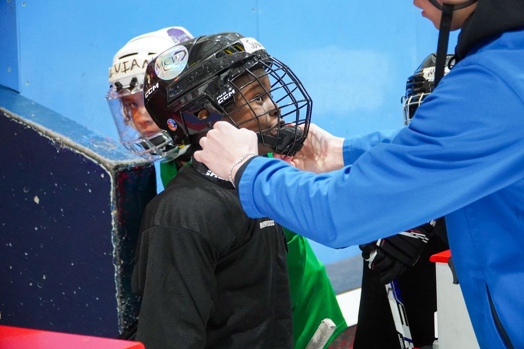 A volunteer fitting a helmet onto a camper at the boards