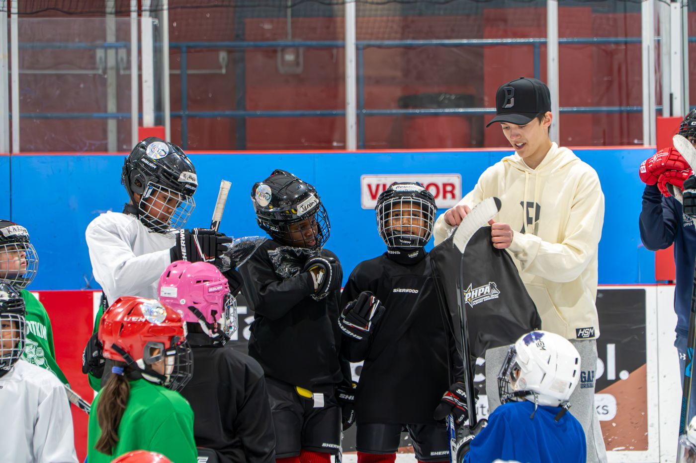 Student volunteers handing out equipment bags to a group of campers gathered along the boards