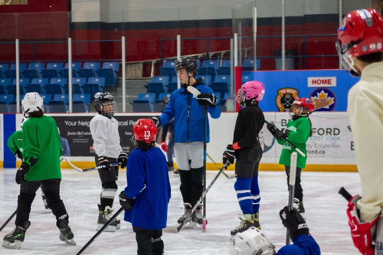 A row of campers in helmets waiting their turn at the side of the rink